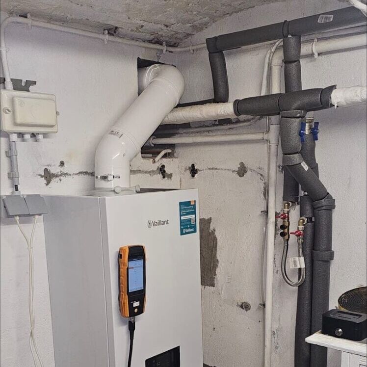Chaudière murale Vaillant avec un appareil de mesure fixé en façade, pendant un contrôle.
