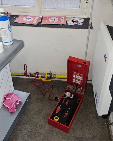 Coffret de contrôle d’étanchéité raccordé à une conduite de gaz jaune.