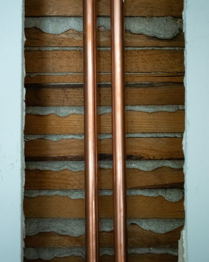 Deux conduites en cuivre posées dans une saignée de mur.